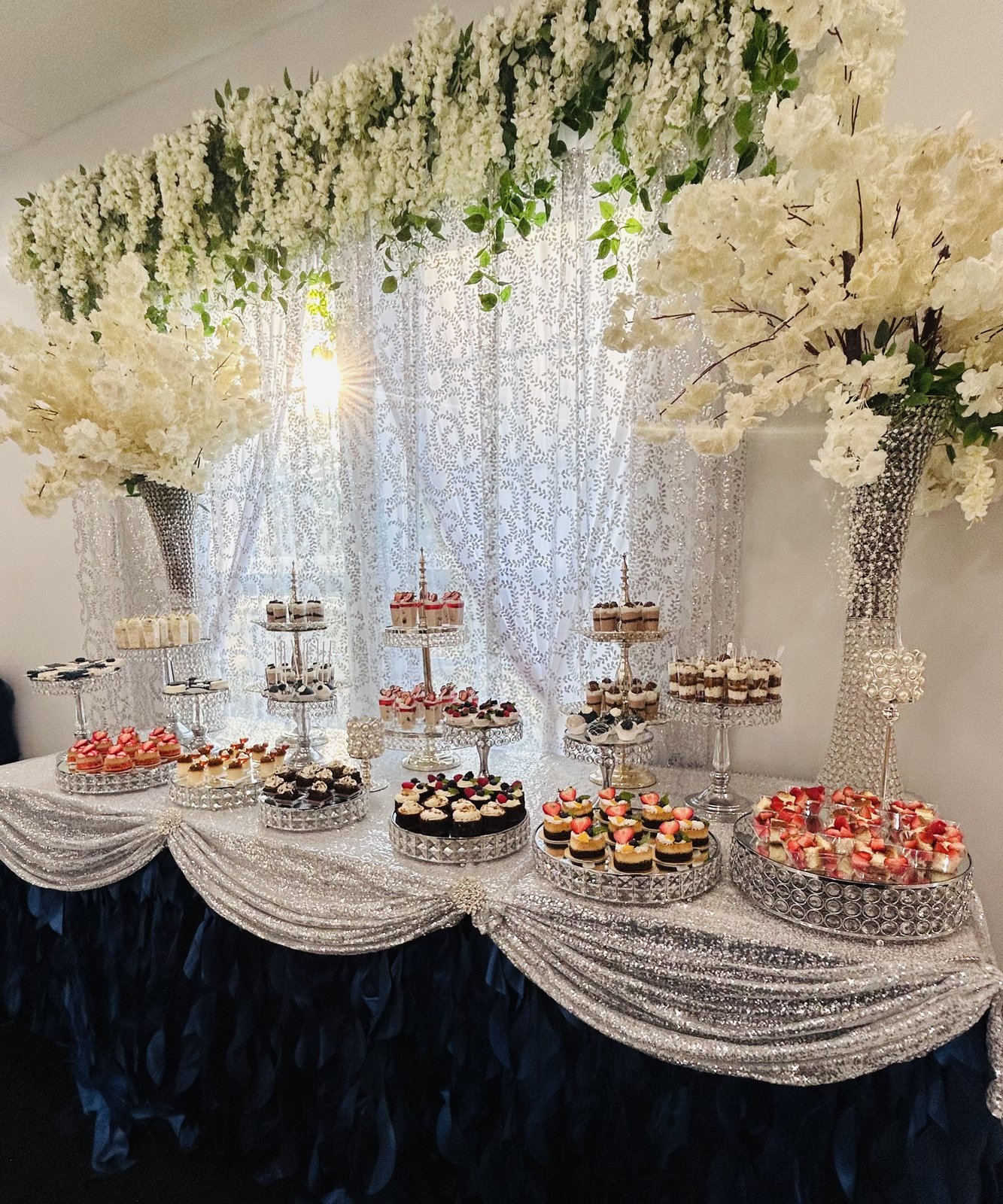 Mesa de postres montada con flores blancas